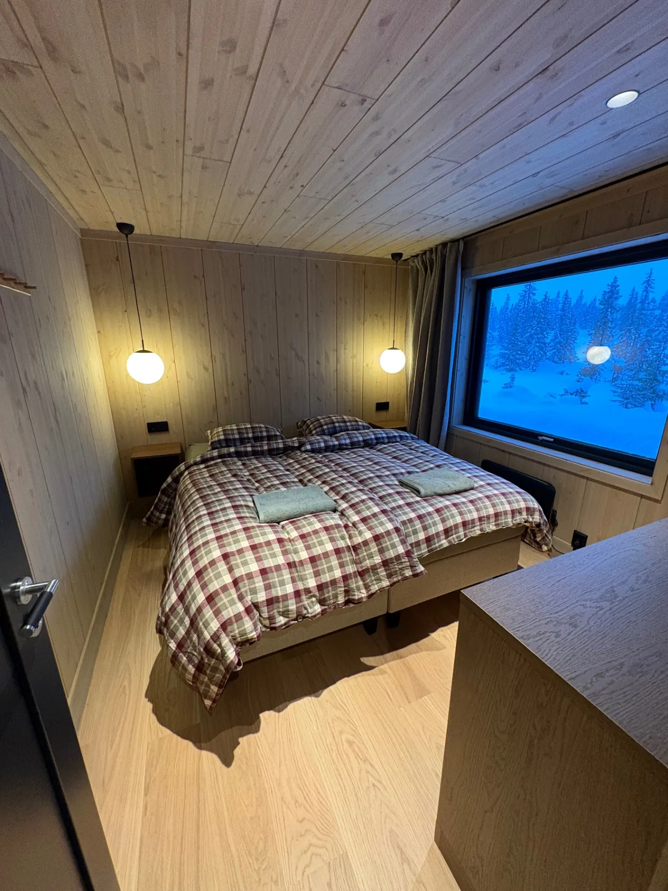 Soverom med stort vindu mot snødekt skog